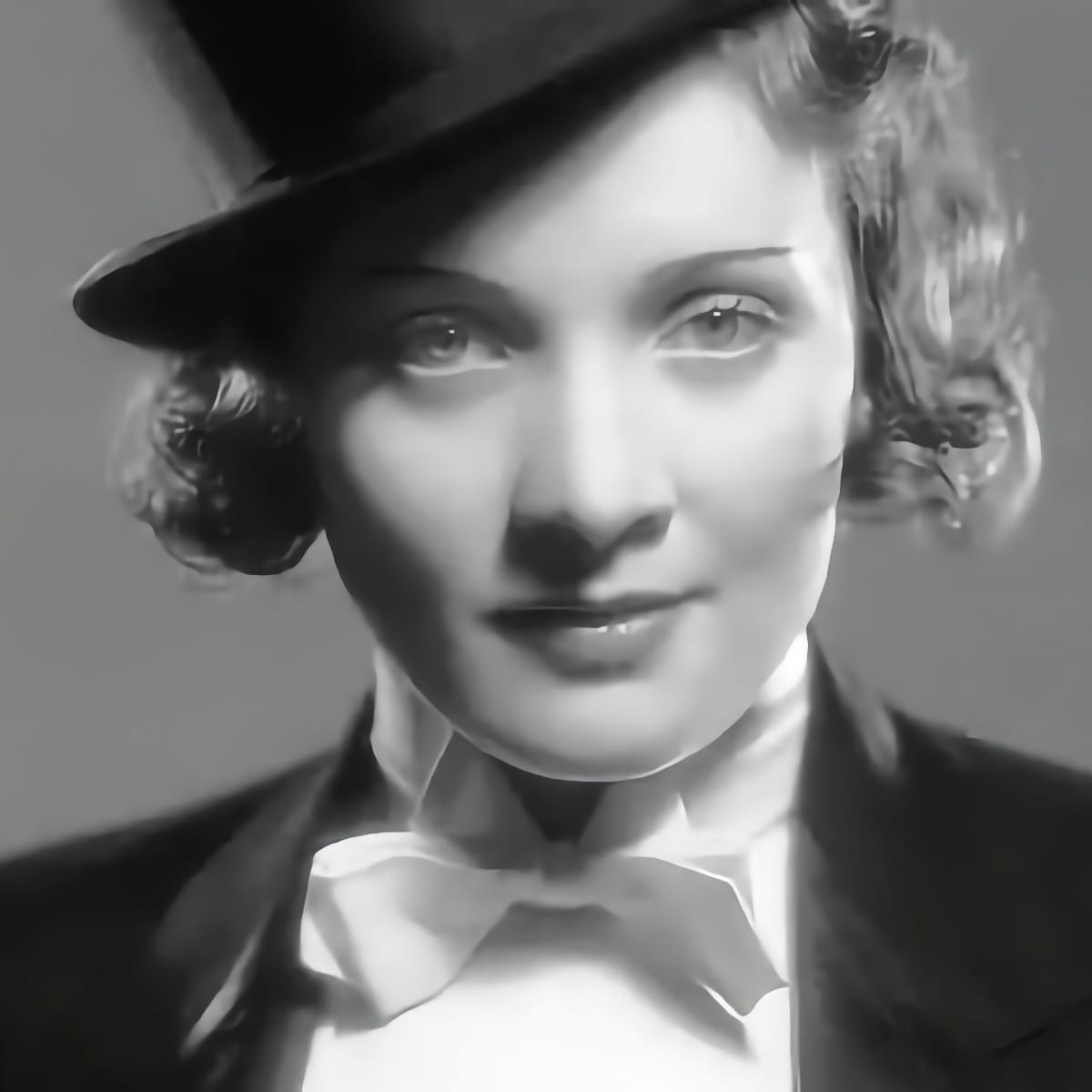 Marlene Dietrich portant un look smoking avec nœud papillon, inspiration androgine.