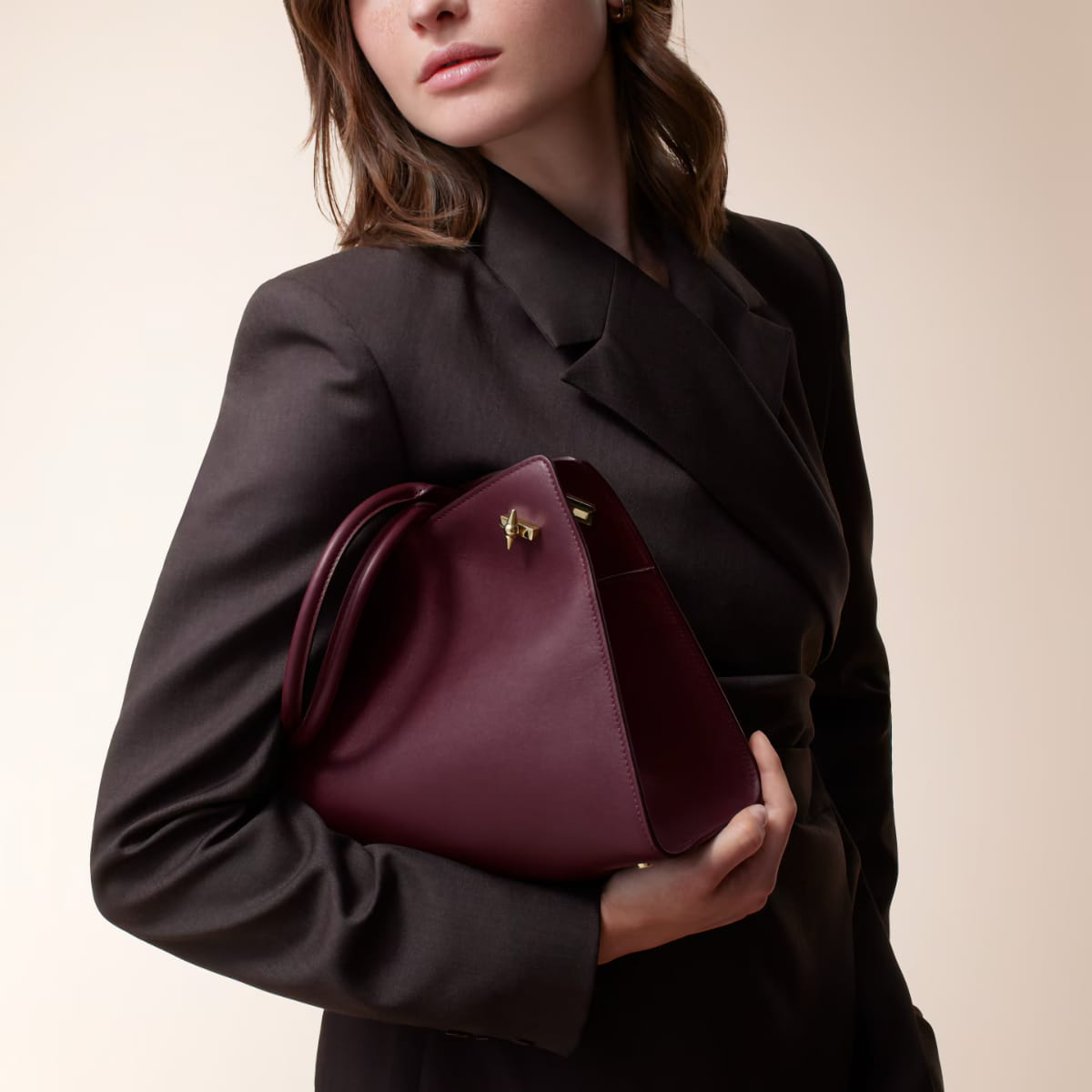 Petit Sac Clash de Cartier bordeaux porté avec un tailleur noir